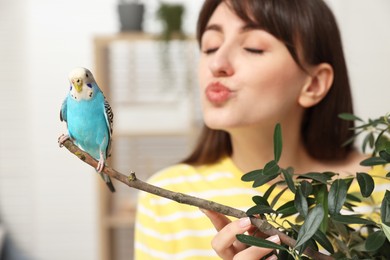 Photo of Woman with bright parrot indoors, selective focus. Exotic pet