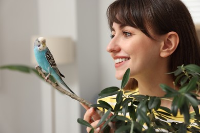 Photo of Woman with bright parrot indoors. Exotic pet