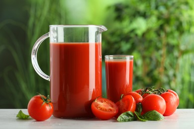 Tasty tomato juice, basil and fresh vegetables on white table outdoors