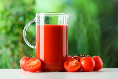 Tasty tomato juice in glass jug and fresh vegetables on white table outdoors