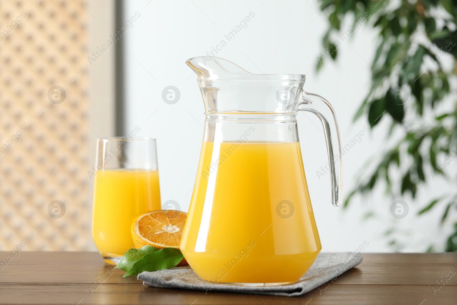 Photo of Tasty orange juice in jug, glass and citrus fruit on wooden table