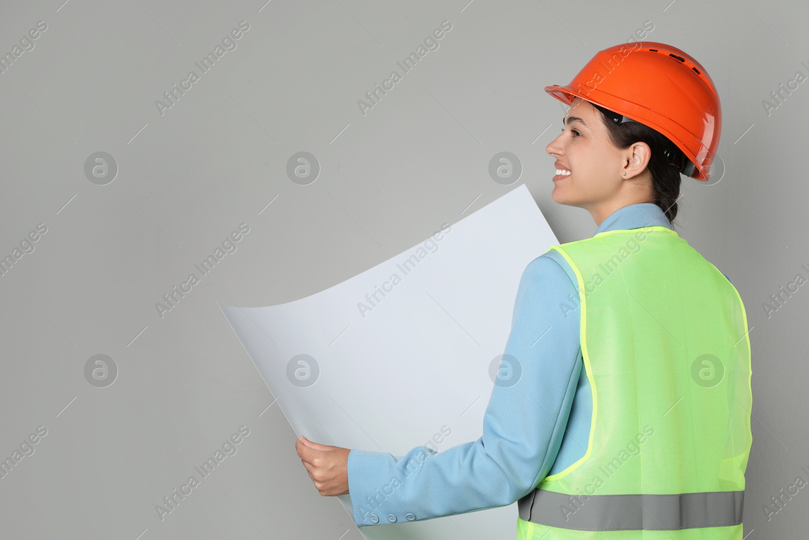 Photo of Engineer in hard hat with draft on grey background, space for text