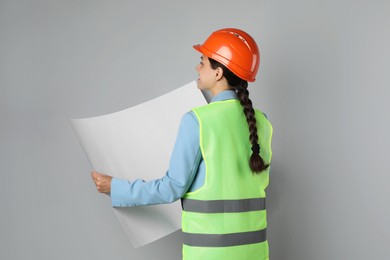 Engineer in hard hat with draft on grey background