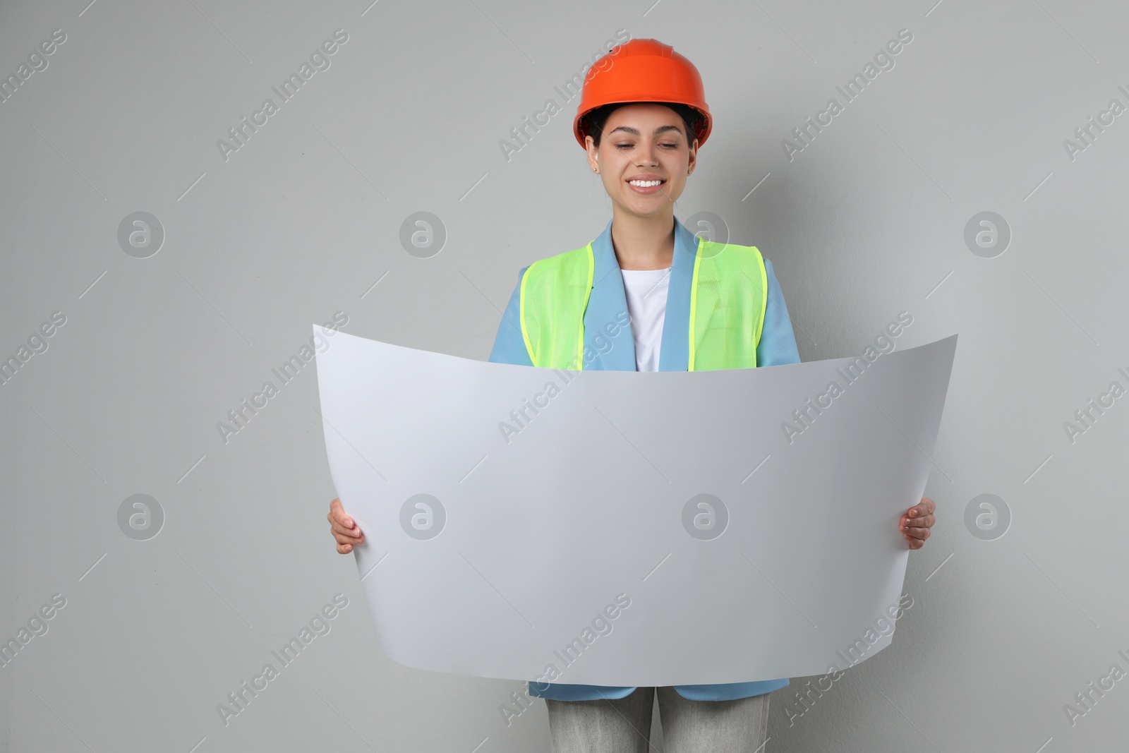 Photo of Engineer in hard hat with draft on grey background