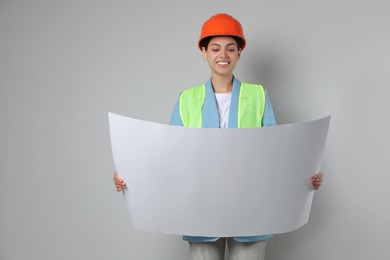 Engineer in hard hat with draft on grey background