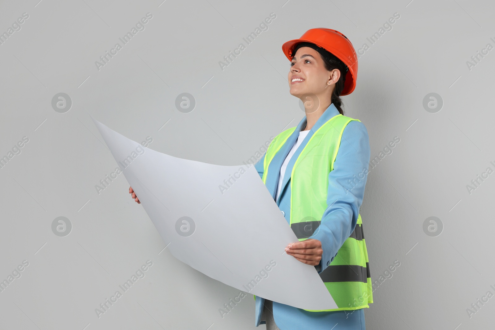 Photo of Engineer in hard hat with draft on grey background