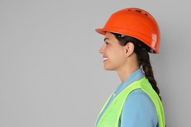 Engineer in hard hat on grey background, space for text