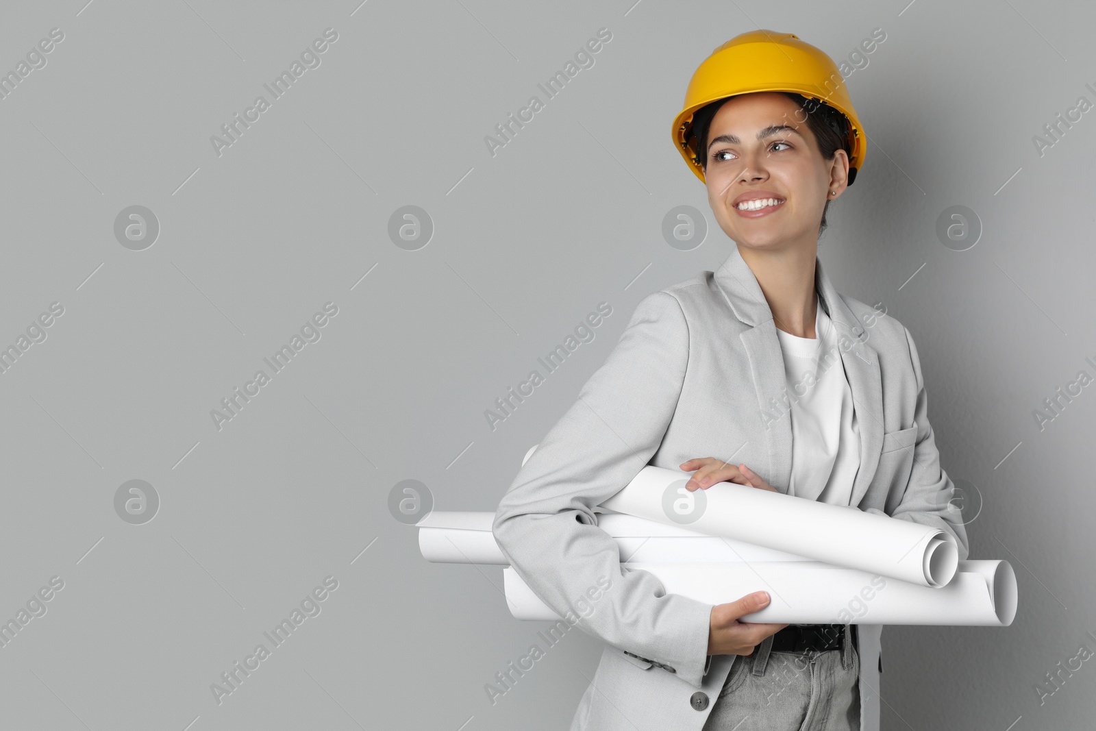 Photo of Engineer in hard hat with drafts on grey background, space for text