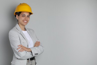 Engineer in hard hat on grey background, space for text