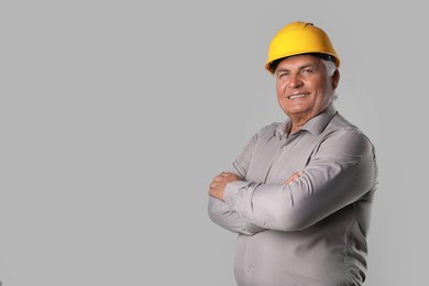 Engineer in hard hat on grey background, space for text