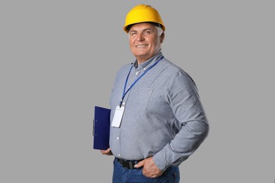 Photo of Engineer in hard hat with clipboard on grey background