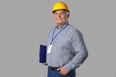 Engineer in hard hat with clipboard on grey background