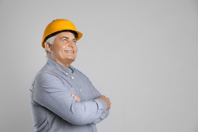 Engineer in hard hat on grey background, space for text