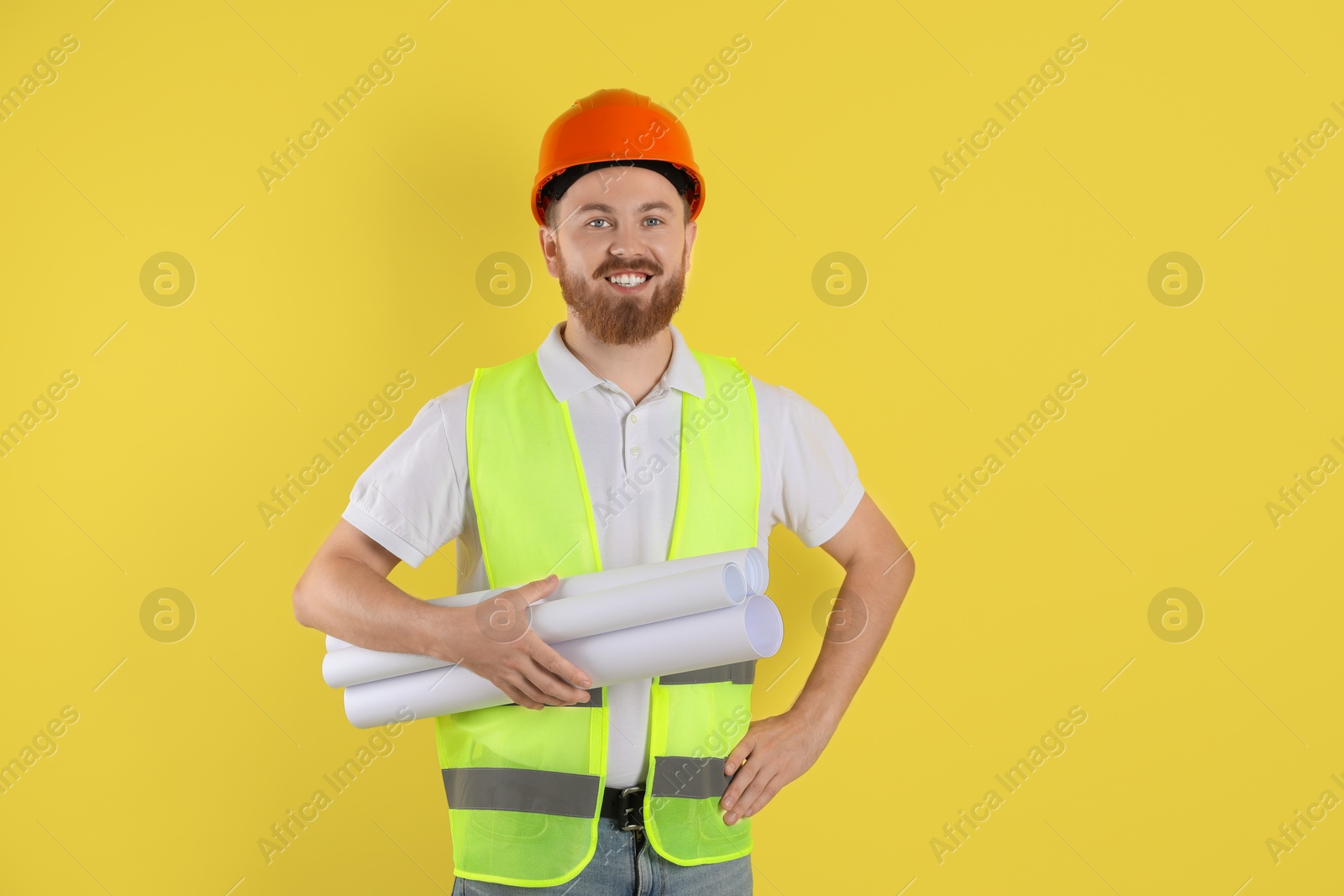 Photo of Engineer in hard hat with drafts on yellow background