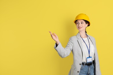 Photo of Engineer in hard hat on yellow background, space for text