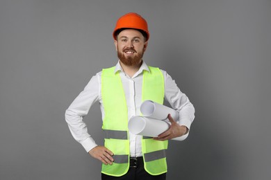 Photo of Engineer in hard hat with drafts on grey background