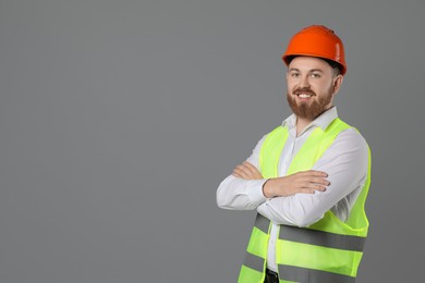 Engineer in hard hat on grey background, space for text