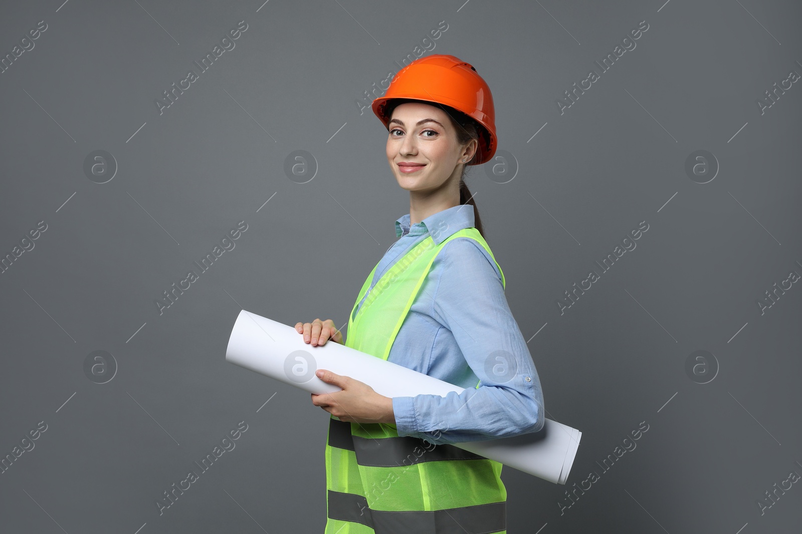 Photo of Engineer in hard hat with draft on grey background