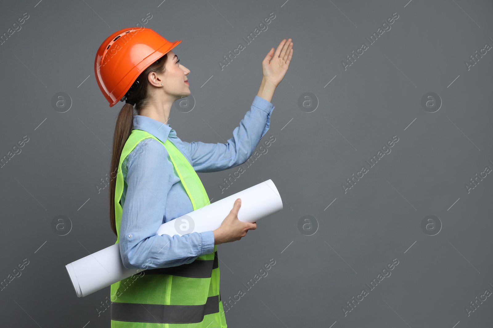 Photo of Engineer in hard hat with draft on grey background, space for text