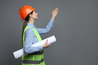 Photo of Engineer in hard hat with draft on grey background, space for text