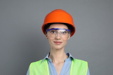 Photo of Engineer in hard hat and goggles on grey background