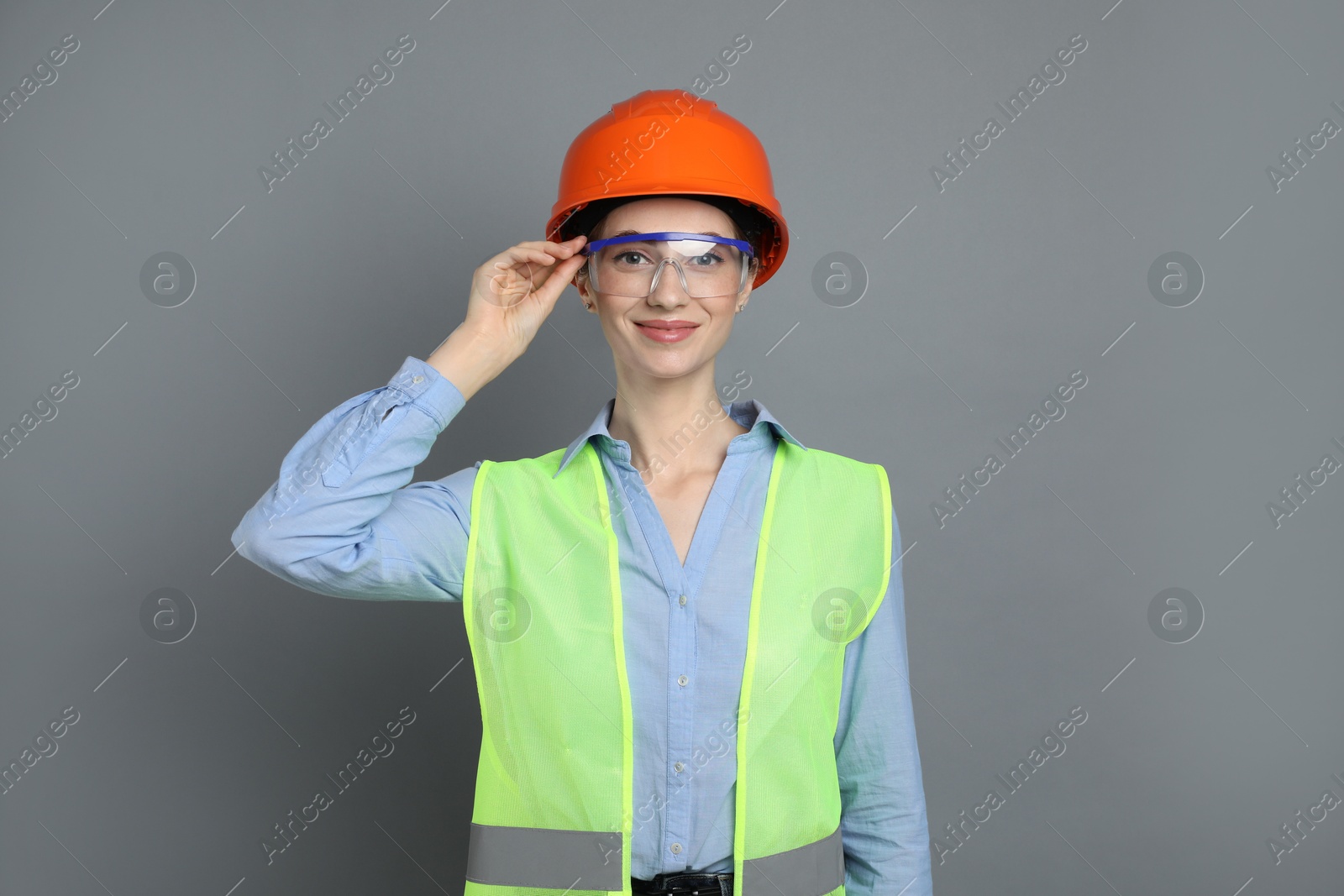 Photo of Engineer in hard hat and goggles on grey background