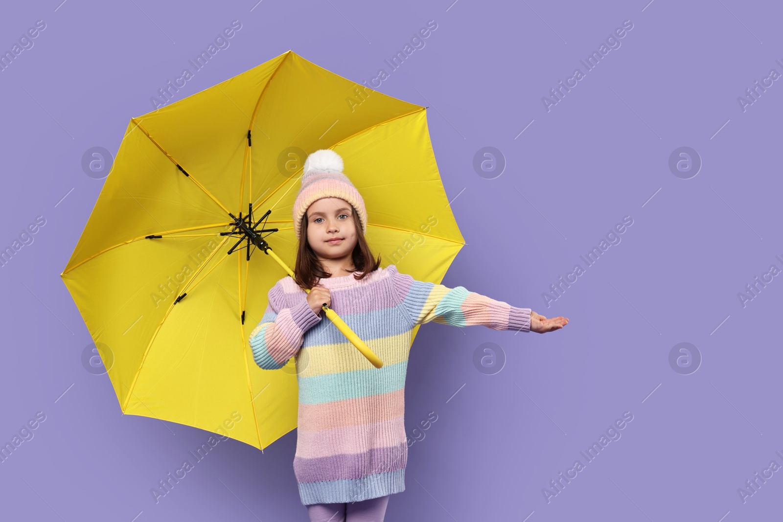 Photo of Cute little girl with yellow umbrella on purple background. Space for text