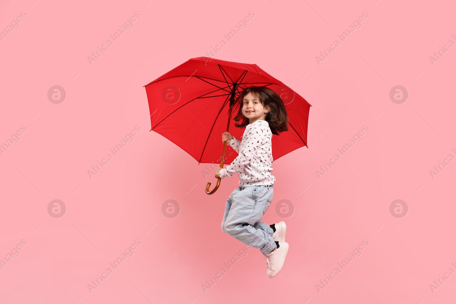 Photo of Cute little girl with red umbrella on pink background