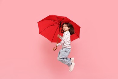 Photo of Cute little girl with red umbrella on pink background