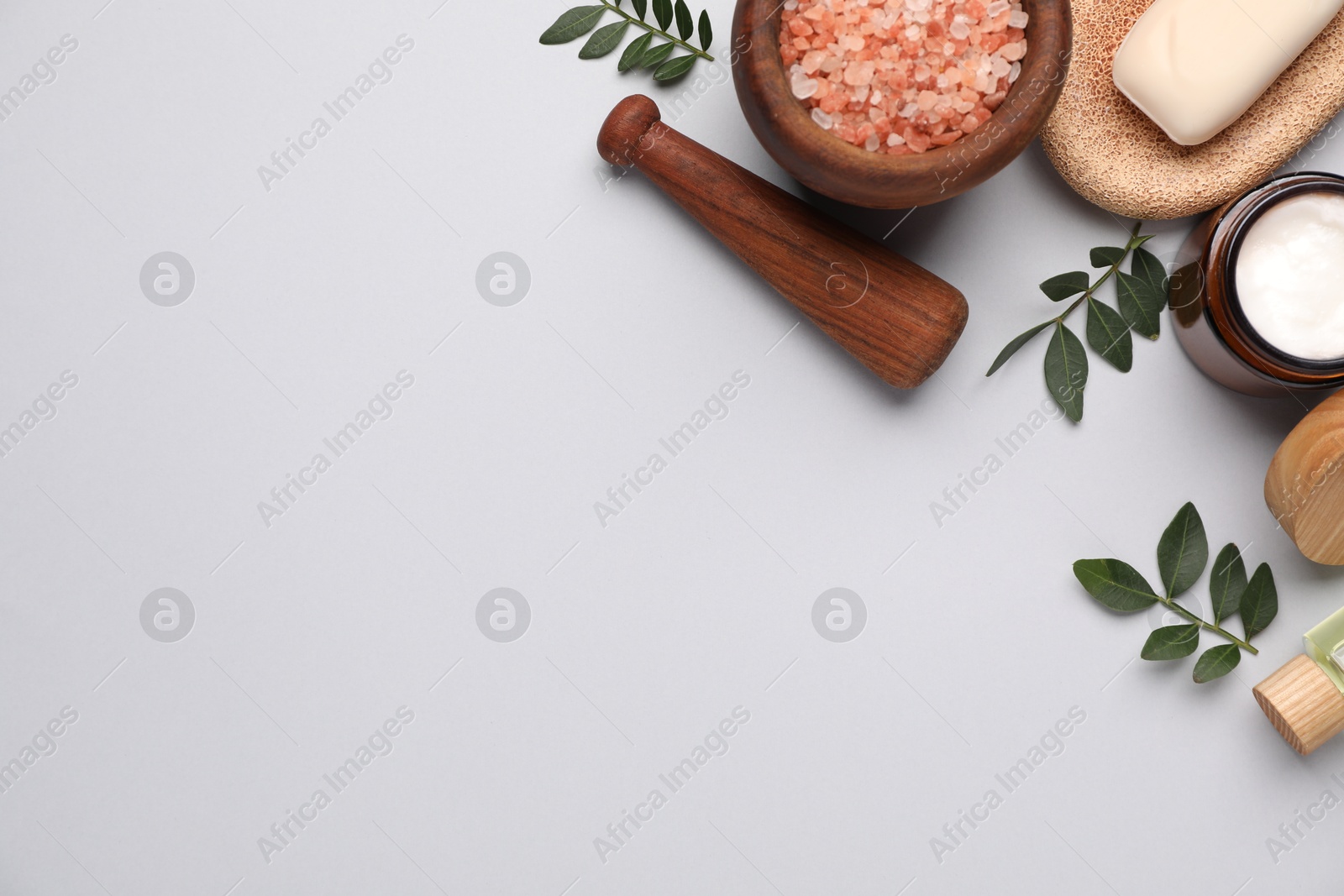 Photo of Different cosmetic products and green leaves on light grey background, flat lay. Space for text