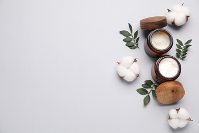 Photo of Different cosmetic products, leaves and cotton flowers on light grey background, flat lay. Space for text