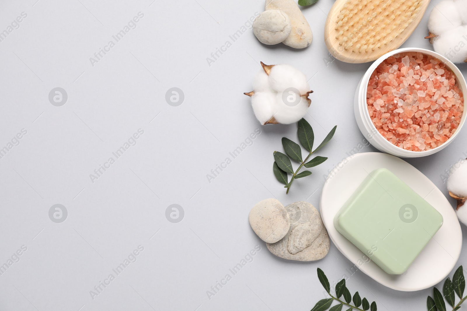 Photo of Different cosmetic products, leaves and cotton flowers on light grey background, flat lay. Space for text