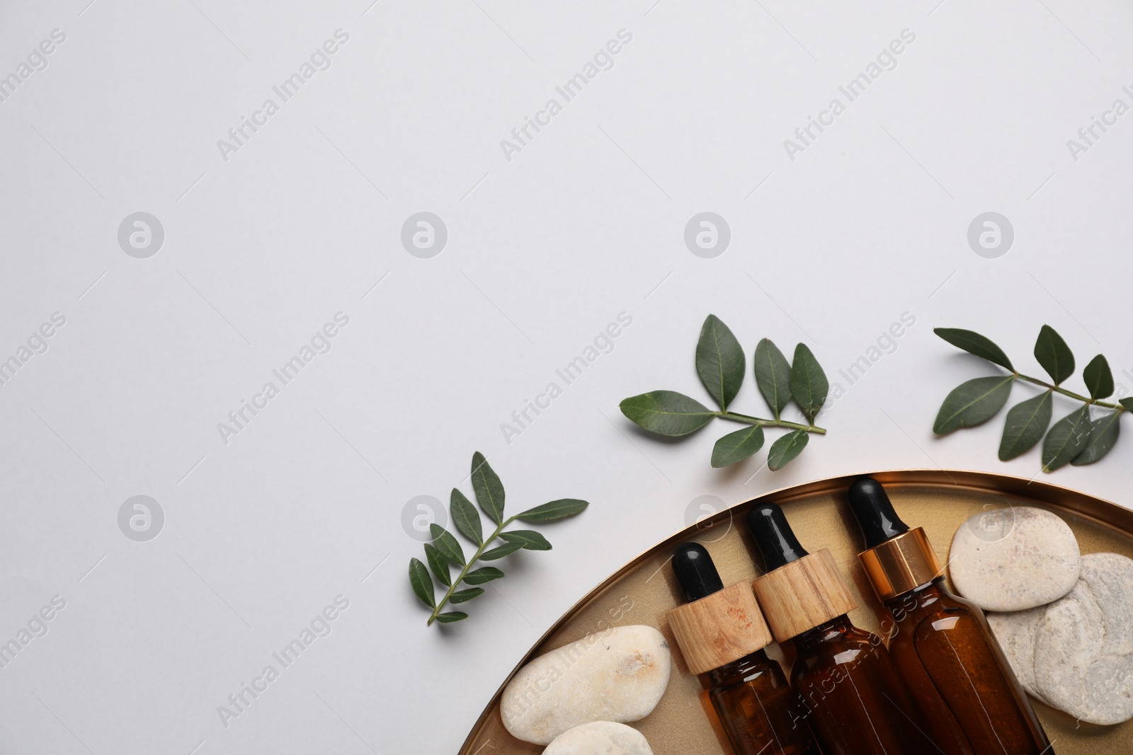 Photo of Different cosmetic products and green leaves on light grey background, flat lay. Space for text