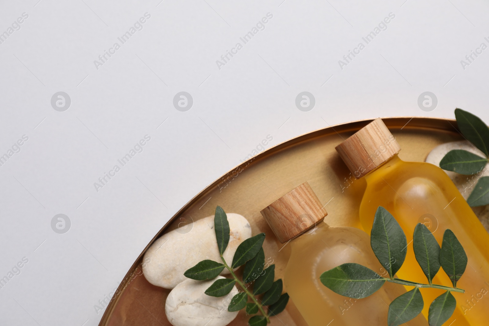 Photo of Different cosmetic products and green leaves on light grey background, top view. Space for text