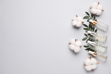 Photo of Cosmetic products, leaves and cotton flowers on light grey background, flat lay. Space for text