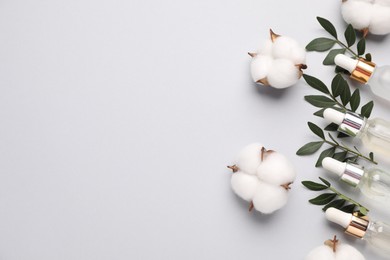 Photo of Cosmetic products, green leaves and cotton flowers on light grey background, flat lay. Space for text