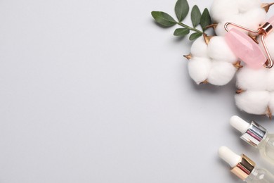 Photo of Different cosmetic products, leaves and cotton flowers on light grey background, flat lay. Space for text