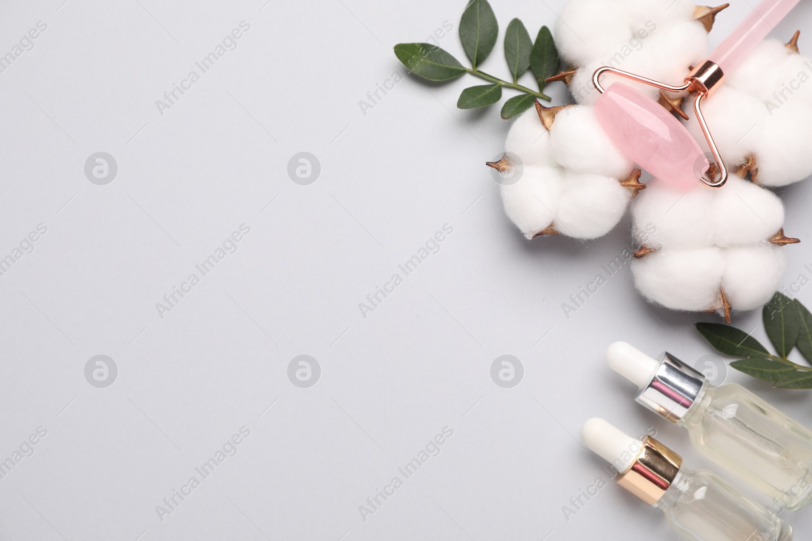 Photo of Different cosmetic products, leaves and cotton flowers on light grey background, flat lay. Space for text