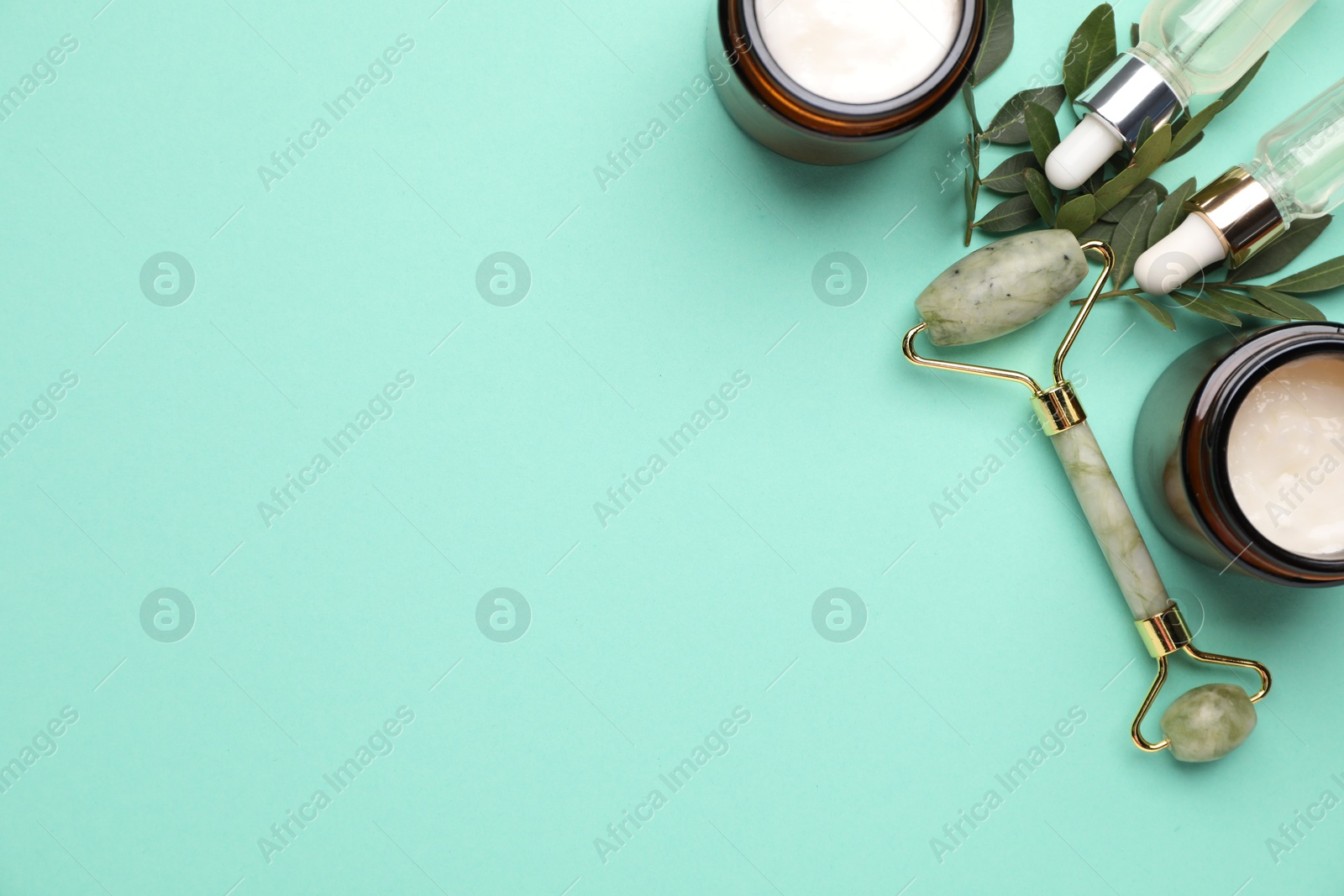 Photo of Different cosmetic products and green leaves on turquoise background, flat lay. Space for text