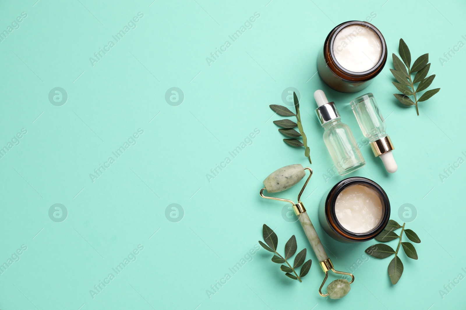 Photo of Different cosmetic products and leaves on turquoise background, flat lay. Space for text