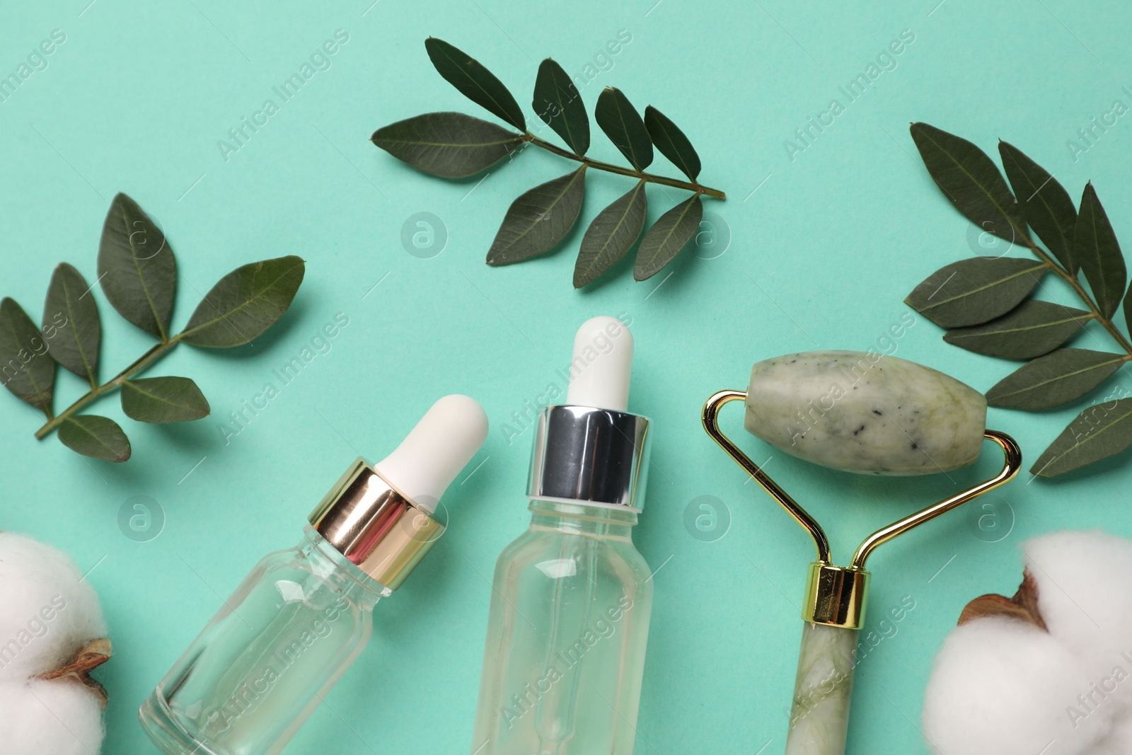 Photo of Different cosmetic products, cotton flowers and green leaves on turquoise background, flat lay