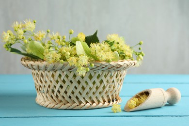 Photo of Fresh linden leaves and flowers in wicker basket on light blue wooden table