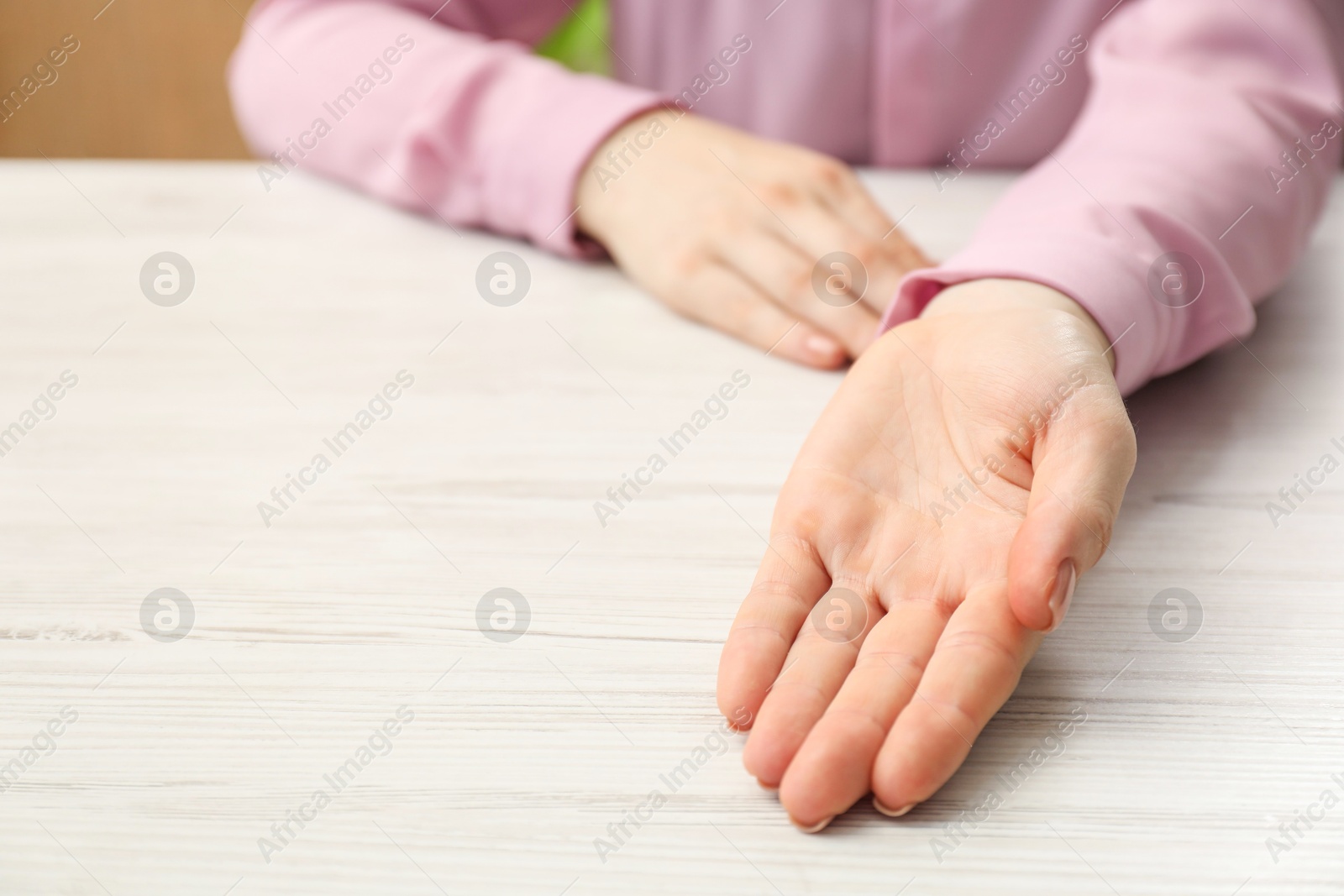 Photo of Chiromancy and foretelling. Woman showing palm at white wooden table, closeup. Space for text