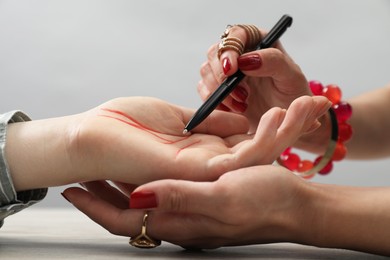 Photo of Fortune teller reading lines on woman's palm at wooden table, closeup. Chiromancy