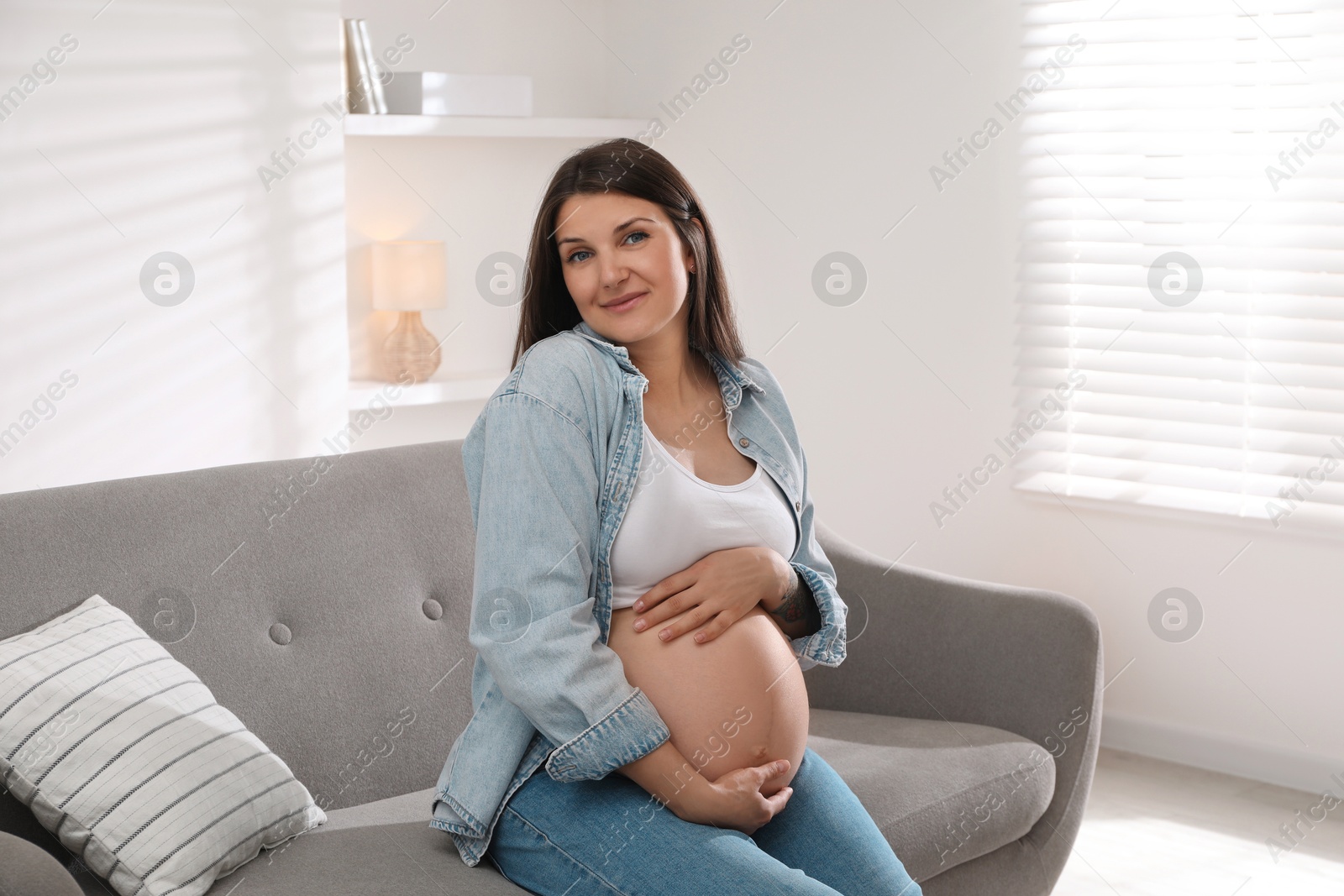 Photo of Beautiful pregnant woman sitting on sofa at home