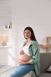 Photo of Beautiful pregnant woman sitting on sofa at home