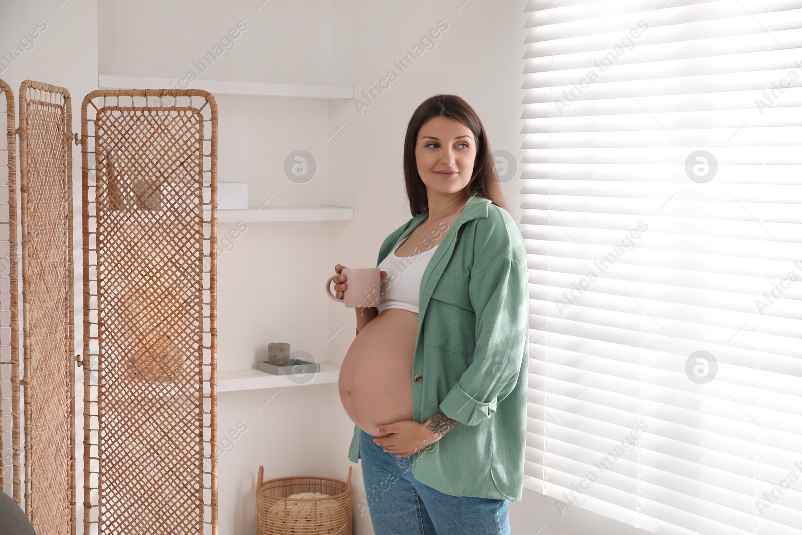 Photo of Beautiful pregnant woman with cup at home