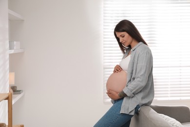 Photo of Beautiful pregnant woman at home, space for text