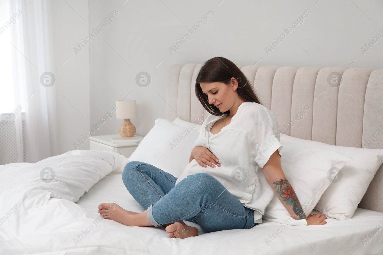 Photo of Beautiful pregnant woman on bed at home