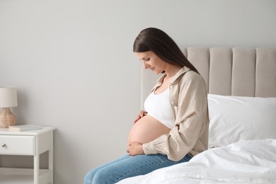 Photo of Beautiful pregnant woman on bed at home